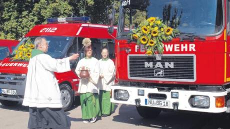 Dekan Johann Huber segnete vor dem Bellenberger Feuerwehrhaus die beiden neuen Fahrzeuge. Rechts der 15 Jahre alte Löschwagen, den die Wehr in Eigenregie umgebaut und modernisiert hatte.  