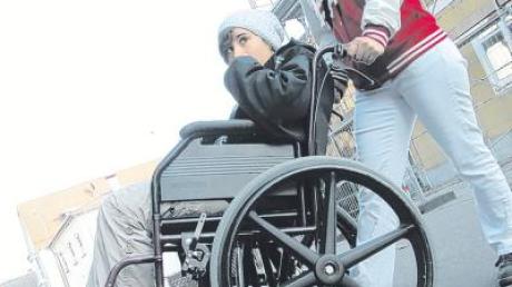 Hier gilt es, einen höheren Randstein zu überwinden, wofür Anna Schwarz mit ihrem rechten Fuß auf die Steighilfe tritt. Im Rollstuhl Verona Venuto.  