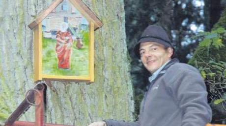 Wolfgang Höß, Bürgermeister von Altenstadt, bringt den runderneuerten Schrein mit dem von Helmut Trautwein renovierten Petrusbild wieder am Baum an. 