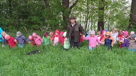 Im nassen Gras auf der Suche nach Rehkitzen und anderen Jungtieren: Kinder des Obenhauser Kindergartens in Begleitung des Bucher Jägers Michael Obst und Kindergärtnerin Tina Unger. 