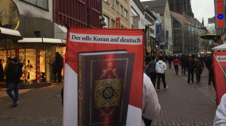 Missionierung mit Münsterblick. Ein Mann verteilt Korane. 