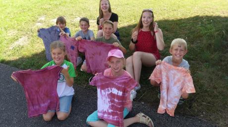 Die Kinder freuen sich über ihre gelungenen Batik-T-Shirts. Hinten im Bild die Betreuerinnen Marlene Geiselmann (links) und Aurelia Koch. 	 	