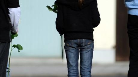 Ein Mädchen, das eine weiße Rose in der Hand hält, steht vor Beginn eines Trauergottesdienstes für die in Krailling grausam ermordeten Geschwister Chiara (8) und Sharon (11) vor der Pfarrkirche St. Elisabeth in Planegg bei München (Oberbayern).