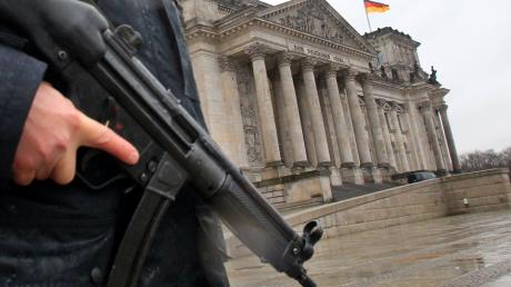 ARCHIV - Ein Polizeibeamter mit einer Maschinenpistole steht am 22.11.2010 vor dem für die Öffentlichkeit gesperrten Reichstag. Die Berliner Polizei hat einen mutmaßlichen islamistischen Terroristen festgenommen. Der 24-jährige Mann soll zusammen mit einem 28-jährigen Komplizen einen Bombenanschlag geplant und dafür Chemikalien bestellt haben. Das sagte ein Polizeisprecher am Donnerstag (08.09.2011). Foto: Wolfgang Kumm dpa/lbn +++(c) dpa - Bildfunk+++