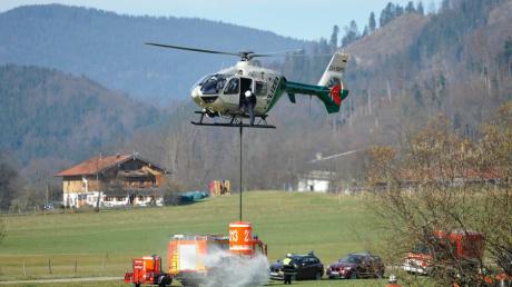 Ein Polizeihubschrauber nimmt am Montag bei Bayrischzell Löschwasser auf, um einen Brand im unwegsamen Berggelände zwischen Seeberg und Rotwand zu bekämpfen. Nach Polizeiangaben erstreckt sich der Brand über eine Fläche von zwei bis drei Hektar.