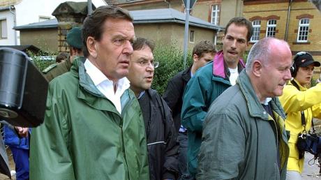 Bundeskanzler Gerhard Schröder (SPD, links) und der sächsische Ministerpräsident Georg Milbradt (CDU) gehen durch die nach dem Hochwasser verwüstete sächsische Kreisstadt Grimma (Archivfoto vom 14. August 2002). 