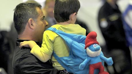 Ein Flüchtlings-Junge aus Syrien sitzt nach der Ankunft am Flughafen auf dem Arm seines Vaters. 