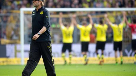 Dortmunds Trainer Jürgen Klopp geht nach dem Spiel vom Platz, während seine Spieler mit den Fans jubeln. 