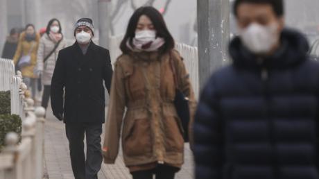 Bürger gehen mit Atemschutz-Masken durch dichten Smog in Peking, China. 