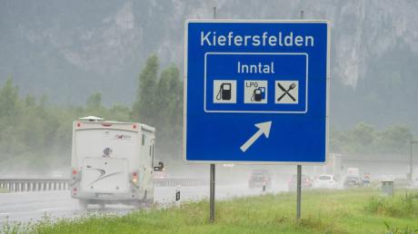 Ein Wohnmobil fährt auf der Autobahn am Verkehrsschild für die Ausfahrt Kiefersfelden (Bayern) vorbei und blinkt. Um Maut zu sparen, fahren viele Urlauber auf Umwegen zu ihrem Ziel. 