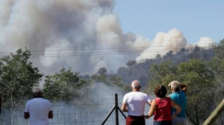Mehrere Menschen schauen in La Londe-Les-Maures auf eine Rauchwolke, die über einem Wald aufsteigt. Hunderte Feuerwehrmänner sind im Einsatz um die zahlreichen Brände zu löschen. 