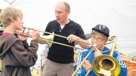 Der Dirigent der Musikkapelle Nattenhausen, Martin Fendt, erklärt den „Jungmusikern“ Thomas Klughammer (rechts) und Andreas Gänzer wie man eine Posaune spielt.  