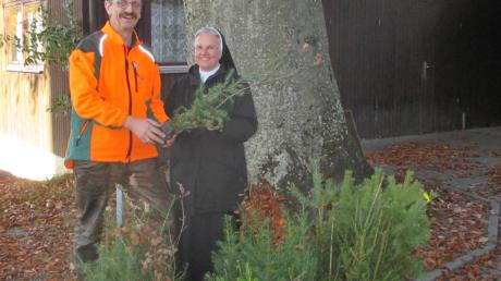 Förster Josef Jäckle übergibt Baumsetzlinge an Sr. Marianne Rauner. Die Jungpflanzen sollen gezielt für den Umbau eines kleinen Waldstückes nahe des Faulbergs eingesetzt werden.  	