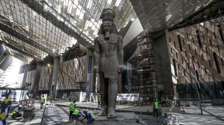 Arbeiter reinigen den Bereich neben der  riesigen Statue des ägyptischen Pharaos Ramses II. in der Halle des Großen Ägyptischen Museums.