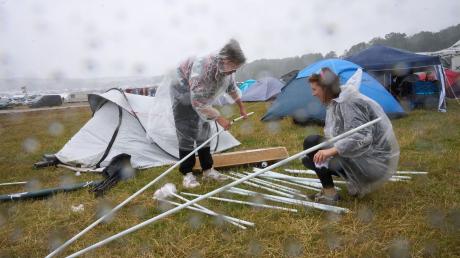 Zwei Fans bauen auf dem Campinggelände des Technofestivals «Nature One» bei strömendem Regen ihr Zelt auf.