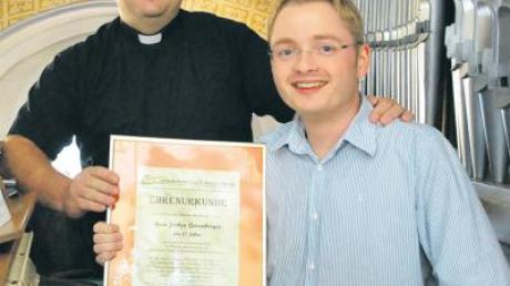 Mit einer Urkunde gratulierte Pfarrer Michael Vogg (links) seinem Kirchenmusiker Jochen Geisenberger zur bereits 15-jährigen Dienstzeit.  