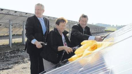 Peer Uhlemann, Thainings Zweite Bürgermeisterin Rita Tagwerker und Thomas Richter (von links) durchschnitten eine sonnengelbe Schleife auf dem ersten Modul des Thaininger Solarparks. 