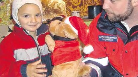 Große Freude über ein kleines Stofftier. Ein Mitarbeiter des Malteser Hilfsdienstes bei er Übergabe eines Geschenks. 