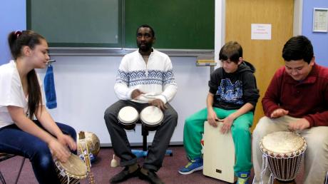 Afrikatag an der Mittelschule Kaufering: Damia, Leon und Ahmet (von links) dürfen gemeinsam mit Njamy Sitson trommeln. 
