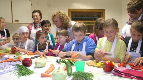 Die Kinder dürfen auch Gemüse schneiden. Angelika Gall, Christa Hirschvogel und Theresa Schuster (hinten von links) unterstützen sie dabei.  

