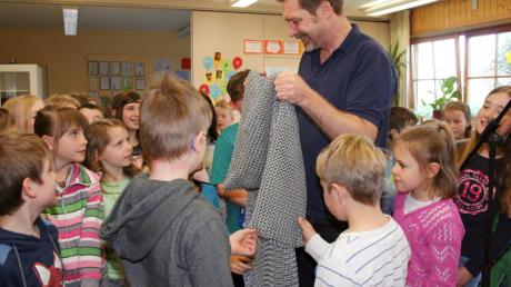Jeder will es mal anfassen: Autor Oliver Pötzsch zeigt den Grundschülern ein Kettenhemd, wie es die Ritter früher trugen. 	 	