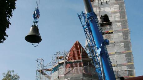 Die größte der vier neuen Bronzeglocken hängt am Haken und wird in Richtung Glockenturm von St. Benedikt aufgezogen.