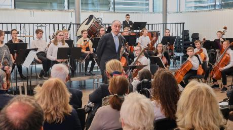 Schulleiter Karl Höldrich bei seiner Begrüßungsrede zur Einweihung der neuen Übungsräume in der Mozartvilla. Im Hintergrund das Schüler- und Jugendorchester der Musikschule Augsburg, das für den musikalischen Rahmen sorgte. 	