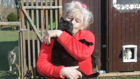 Roswitha Fuchs auf ihrem Gelände in Göggingen mit einigen ihrer geretteten Katzen und Hunde, auf ihrem Arm hat sie Kater Ringo, der freiwillig in ihre Arme springt. 	