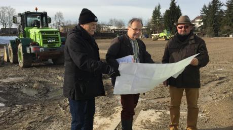 Anton Wolff, Peter Sterz und Stefan Oberschmid (von links) sehen sich die Pläne für den Bau des Hybridrasenplatzes an. 	