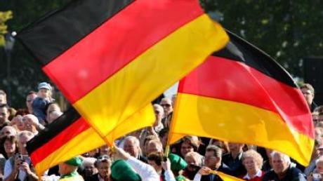 Eine Trachtengruppe präsentiert bei der Musikparade zum Tag der Deutschen Einheit die deutschen Farben.