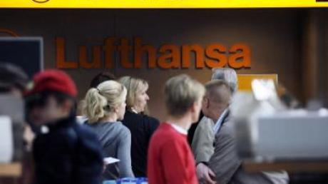 Passagiere der Lufthansatochter CityLine warten am Hamburger Flughafen am Ticketschalter. (Archivfoto)
