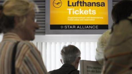 An einem Schalter der Fluggesellschaft Lufthansa warten Passagiere auf dem Flughafen in Berlin-Tegel auf ihre Flugscheine.