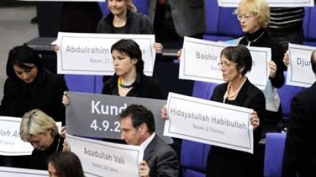 Abgeordnete der Linken halten im Bundestag Plakate mit Namen von Opfern des umstrittenen Luftschlags in Kundus in Afghanistan.