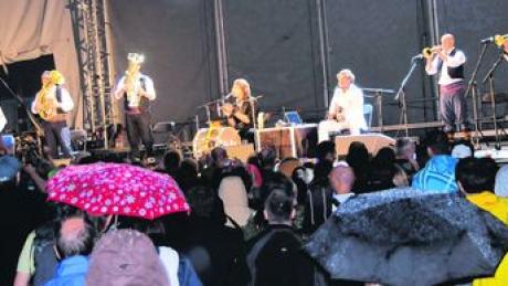 Musikgenuss unter dem Regenschirm: Das Konzert von Goran Bregovic (dritter von rechts) und seiner "Wedding and Funeral Band" litt unter dem miesen Wetter. Foto: Roland Furthmair