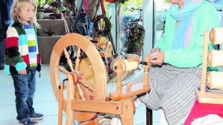 Die kleine Besucherin staunt: Carmen Sendelbach lässt ihr Spinnrad surren. Foto: grr