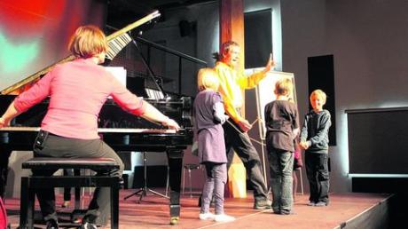 Wie funktioniert das mit den Saiten im Klavier? Marko Simsa, seine Pianistin Barbara Rektenwald und Kinder aus dem Publikum probieren es aus. Foto: Jakob