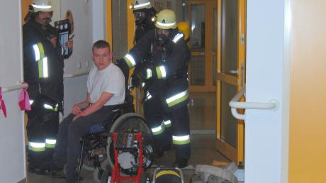 Training für einen Ernstfall, der hoffentlich nicht eintritt: Atemschutzträger bergen einen schwerbehinderten Bewohner aus dem Wohnbereich im zweiten Stock.