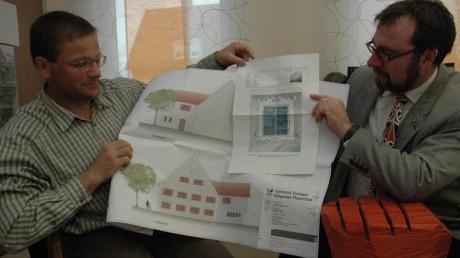 Bürgermeister Robert Sturm (rechts) und sein Gemeinderatskollege Markus Maier präsentieren den Plan des Mesnerhauses und eine Detailansicht der reizvollen historischen Fenster. 
