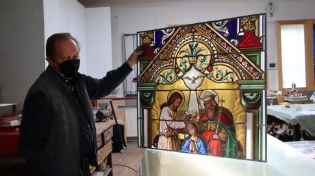 Handwerksmeister Josef Kunder hat in unzähligen Stunden an der Restaurierung der beiden Kirchenfenster gearbeitet. Ein wenig Licht, das durch das Atelierfenster fällt, lässt das Teilstück von „Maria Krönung“ leuchten.  