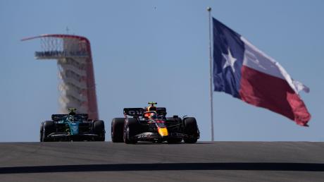 MotoRed-Bull-Pilot Sergio Perez (r) aus Mexiko, und Aston-Martin-Pilot Sebastian Vettel (l) aus Deutschland, steuern durch eine Kurve vor der Flagge von Texas.