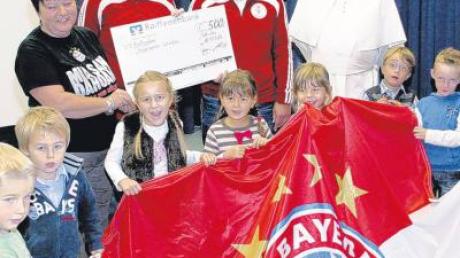 Die Bayernfans überreichen das „Lösegeld“ an die Kinder (hinten von links): Christine Harder, Roland Held, Arnulf Strobel und Pater Johannes Baptist.  