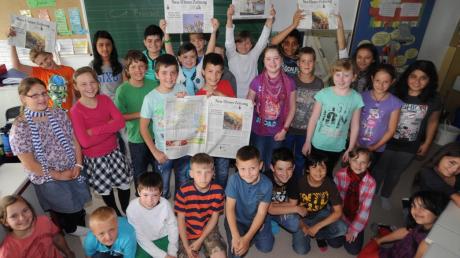 Die Schüler der Klassen 4c und 4d der Erich-Kästner-Grundschule halten begeistert die Neu-Ulmer Zeitung in die Höhe. 
