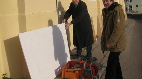 Billig, schnell und wirkungsvoll: Gestern hat Zimmermann Hans Kienzle (rechts) mit dem Bau der Bretterwand an der Witzighauser Pfarrkirche begonnen. Bürgermeister Baiker begutachtet die Arbeit. 
