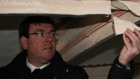 Regionaldekan Pfarrer Werner Dippel begutachtet die Schäden an den Chorrippen in der Burgheimer Pfarrkirche. 

