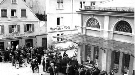 Das Bild zeigt die Nordwestseite des Schrannenplatzes mit Markthaus um 1920, dahinter das Zeugmacherhaus C47 (mit Beschriftung „Eduard Rumpf“), später Modegeschäft der Familie Neumeier. 	