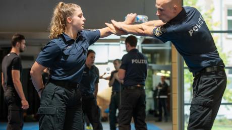 Eine Polizeischülerin trainiert im Rahmen ihrer Ausbildung,  wie man einen Messerangriff abwehrt. Geübt wird mit einer Plastikflasche anstelle des Messers.