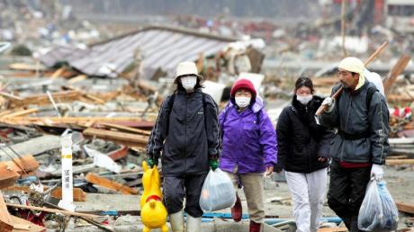Eine japanische Familie verlässt die zerstörte Stadt Minamisanriku. dpa