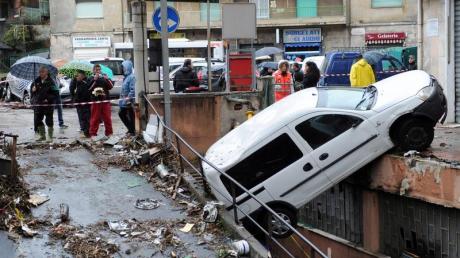 Ein Auto, das die Flut mitgerissen hatte, ist an einer Mauer hängengeblieben. Foto: Alessandro di Marco. dpa
