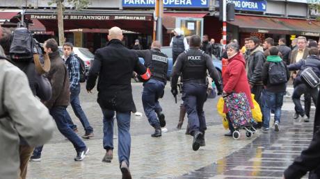 Flucht vor den Schüssen: Polizisten mit gezogenen Pistolen und Passanten laufen über den Place Saint-Lambert in Lüttich.