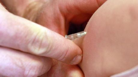 Ein Kinderarzt gibt einem Mädchen eine Masernimpfung.
